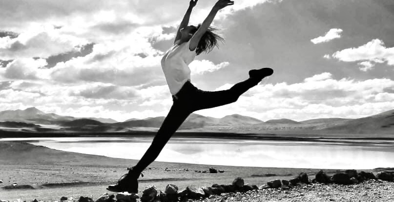 Verina leaping beside a mountain lake